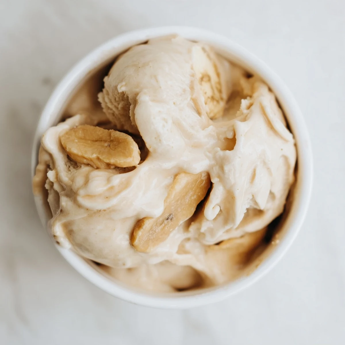 Creamy Peanut Butter Banana Ice Cream swirled in a bowl, perfect for a refreshing, dairy-free dessert on a hot day.