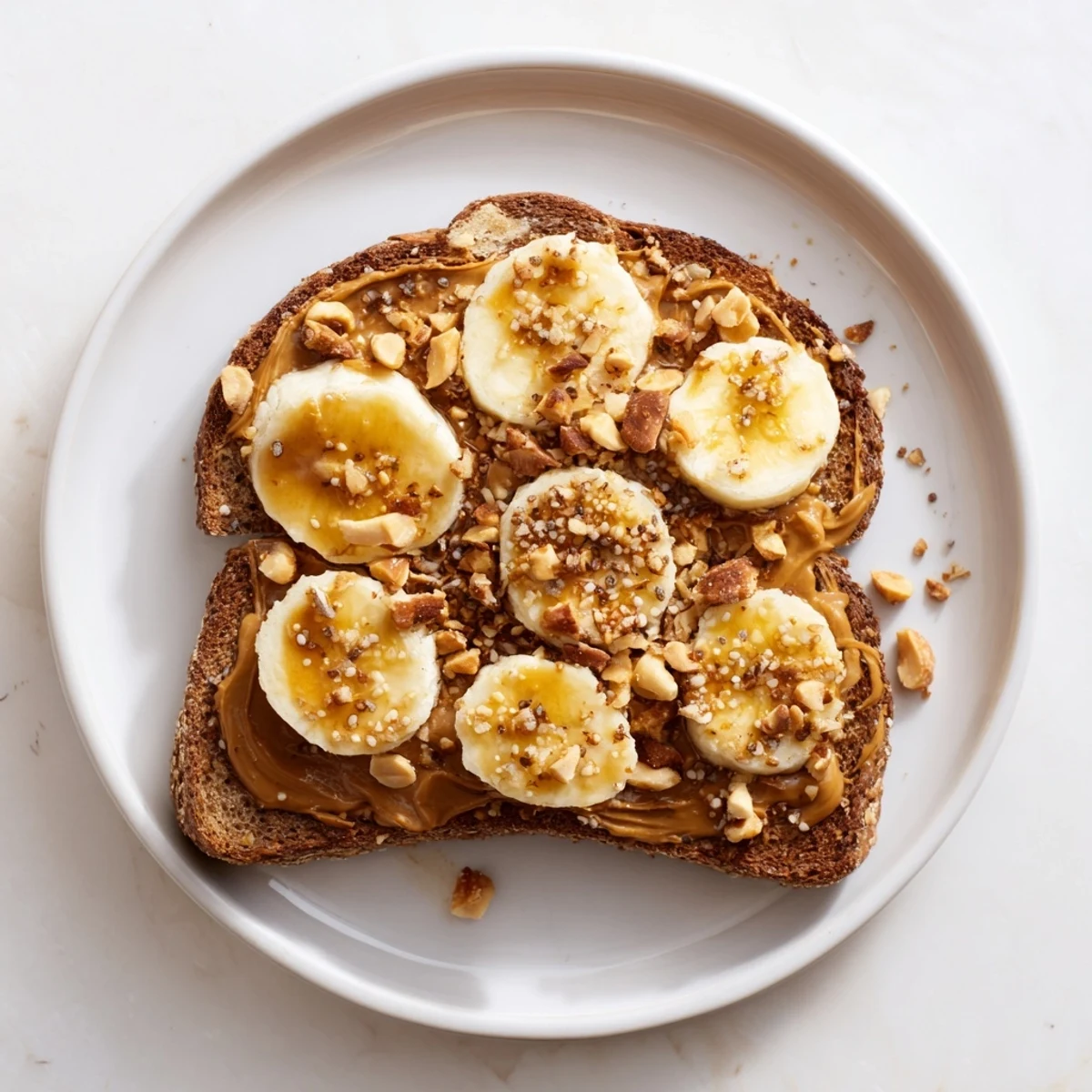 Texture-rich peanut butter and banana sandwich featuring toasted bread, roasted peanuts, and granola for snacking.