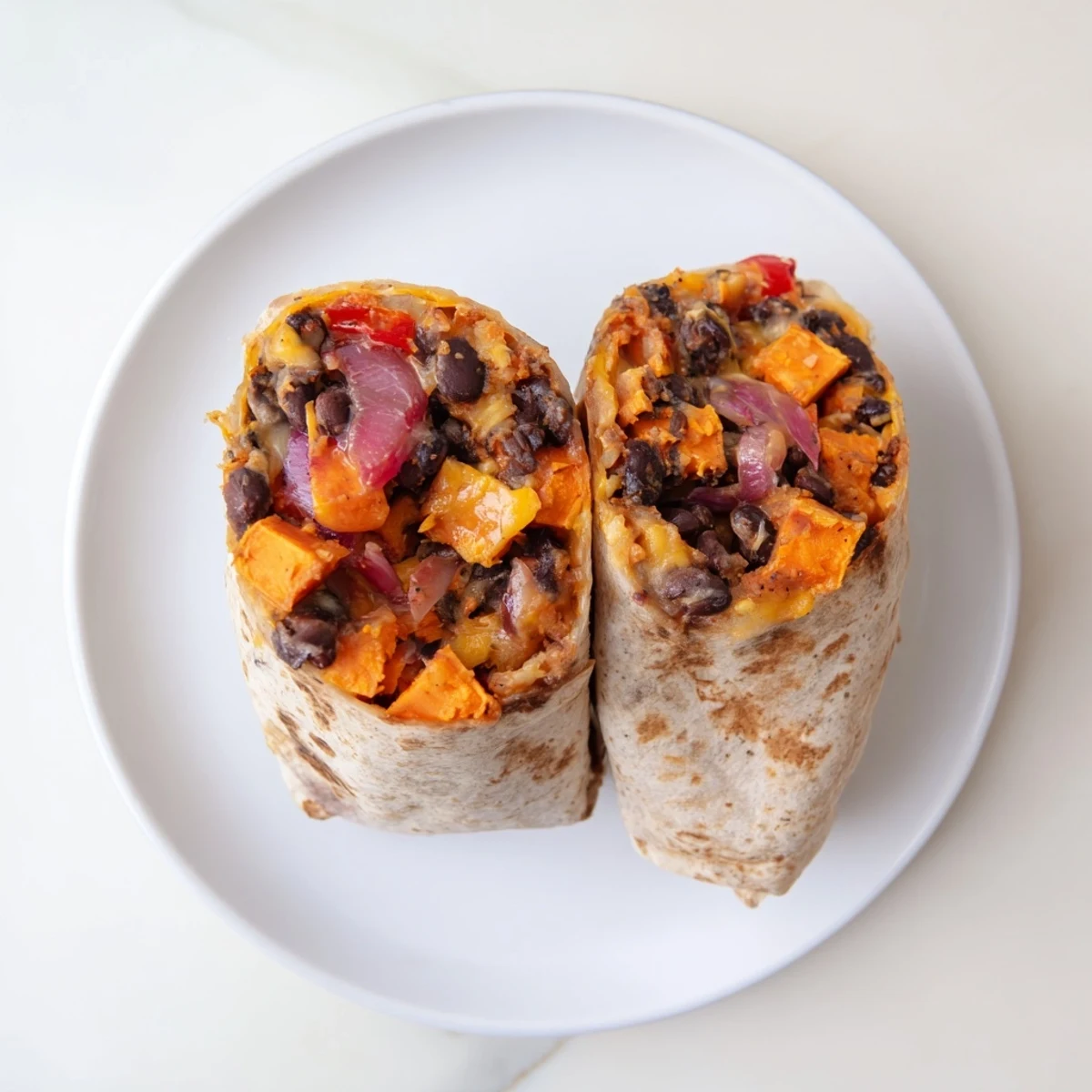 A close-up of a warm Sweet Potato & Black Bean Breakfast Burrito, perfectly wrapped and ready to eat.