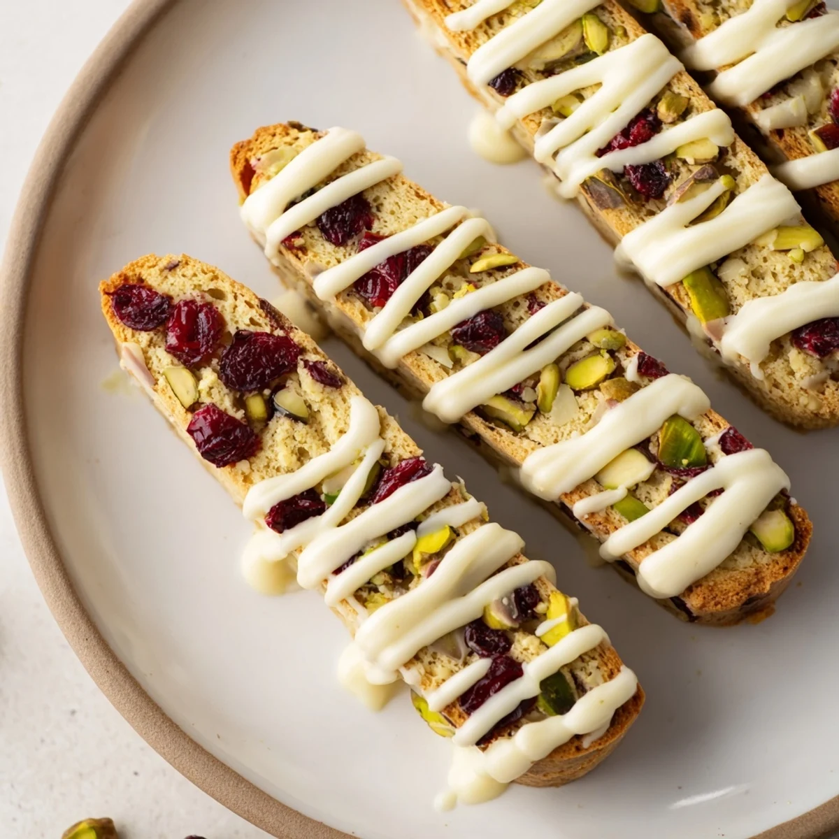 Close-up of golden-brown White Chocolate Cranberry Pistachio Biscotti ready to dunk in a warm beverage.