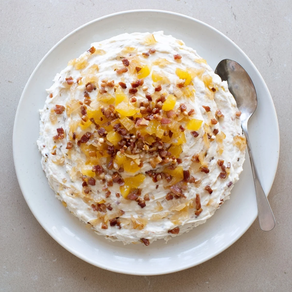 A close-up of creamy Caramelized Onion and Bacon Dip, ready to scoop with crunchy chips.