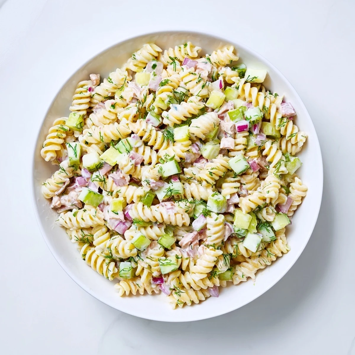 Creamy dill pickle pasta salad, tossed with cheddar, herbs, and ready for a summer picnic.