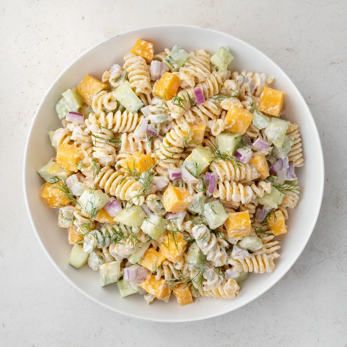 Vibrant dill pickle pasta salad features cubed cheddar and fresh dill, a perfect vegetarian dish.