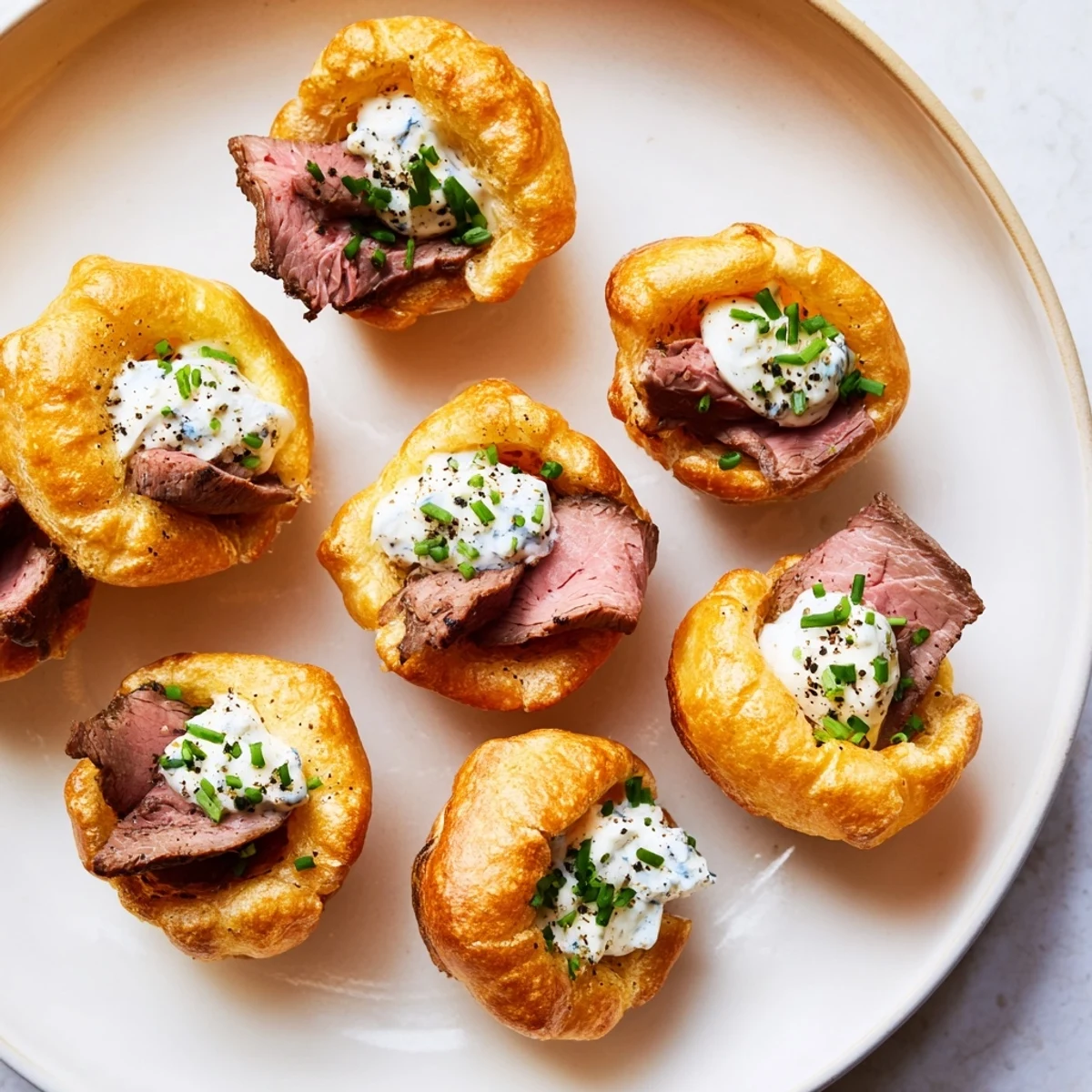 Crispy Express Holiday Yorkshire Pudding Bites, ready to eat, topped with roast beef and fresh chives.