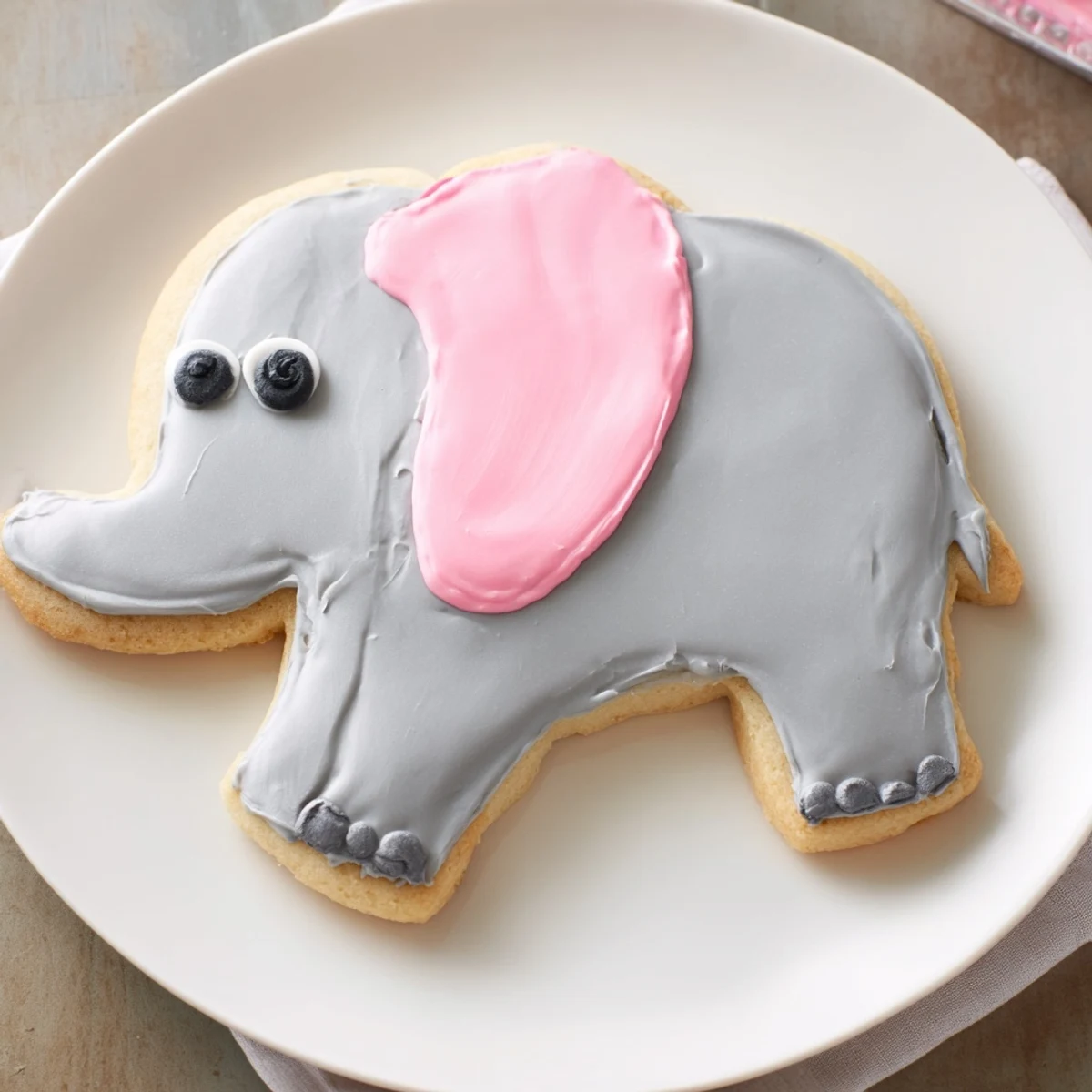 Freshly baked Biscuits Amical Éléphant Géant cookies, featuring gray icing and adorable pink ears, waiting to be served.