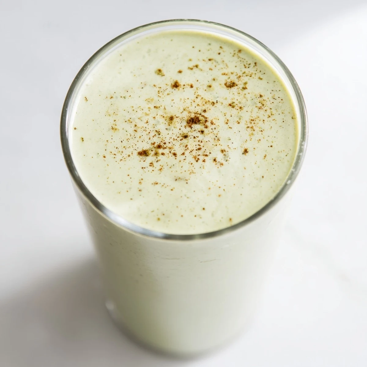 Creamy Matcha Eggnog Collagen Breakfast Smoothie: chilled, festive drink garnished with nutmeg, perfect for a fast start.