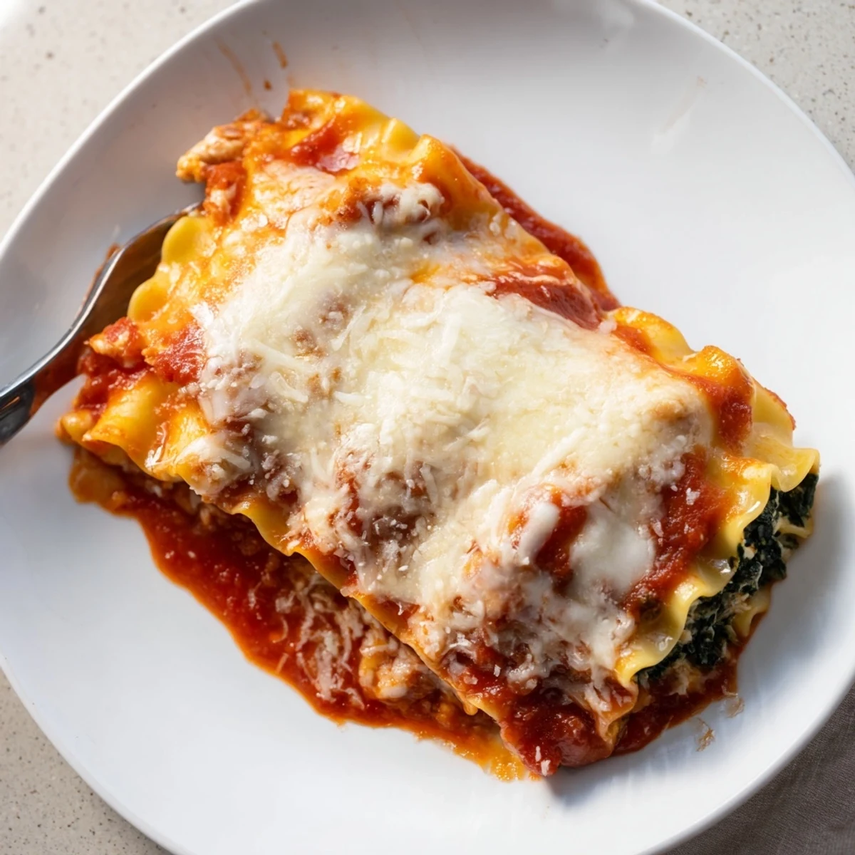 Savory Chicken and Spinach Lasagna Rolls in a rich marinara sauce, garnished with fresh parsley for a hearty Italian-American dinner.