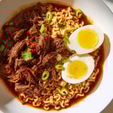 Tender, spiced beef beautifully tops a bowl of Chaos Cooking Birria Ramen, a fusion of flavors.