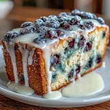 Tender lemon cake dotted with fresh blueberries and topped with a sweet, tangy lemon glaze, ideal for celebrations.  
