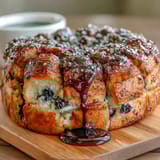 Golden sourdough pull-apart loaf filled with vibrant blueberries and zesty lemon sugar, baked to perfection for a sweet brunch treat.  