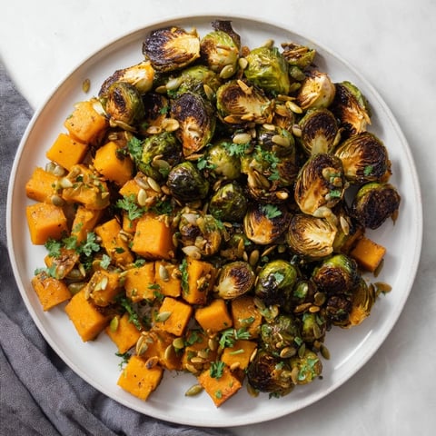 Golden-brown roasted Brussels sprouts and butternut squash with bright orange dressing, ready to enjoy.
