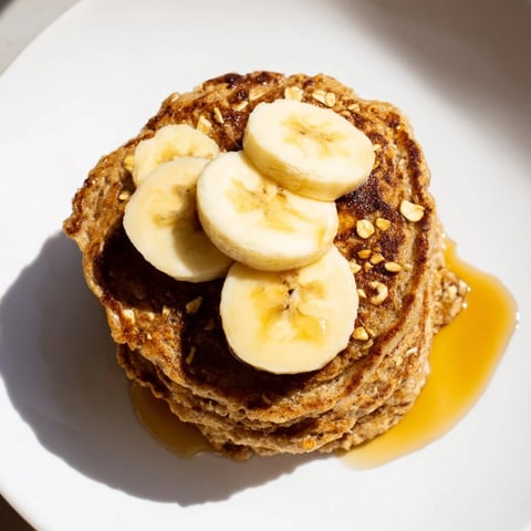Golden-brown banana oat pancakes stacked high, ready to be drizzled with sweet maple syrup.