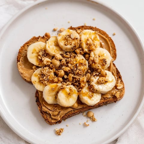 Golden-brown peanut butter and banana sandwich, drizzled with honey, ready to eat with crunchy toppings.