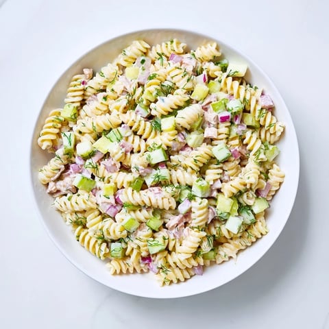 Creamy dill pickle pasta salad, tossed with cheddar, herbs, and ready for a summer picnic.