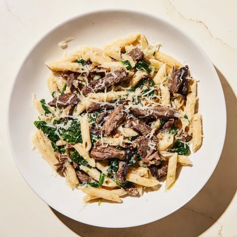 Steaming hot Steak & Spinach Artichoke Pasta Bake with melty mozzarella, ready for enjoyment with a fork.