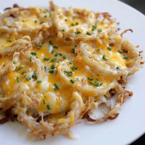 Golden, crispy onion cheese chips piled ready for snacking, with melted cheese and fresh herbs.