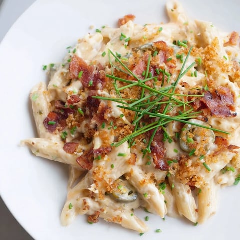 Creamy jalapeño popper pasta topped with crispy bacon, roasted jalapeños, and golden panko breadcrumbs in a white bowl.