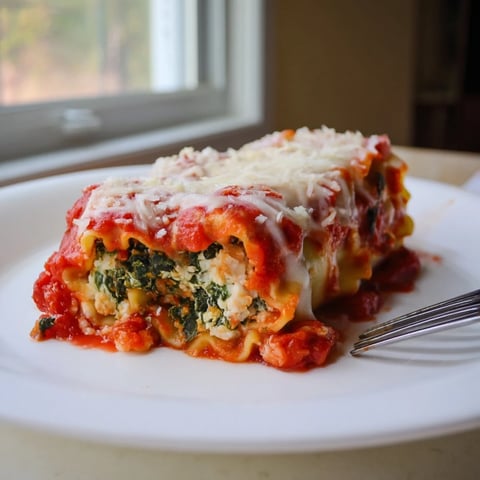 Golden-brown Chicken and Spinach Lasagna Rolls filled with creamy ricotta and spinach, topped with marinara and melted mozzarella.  