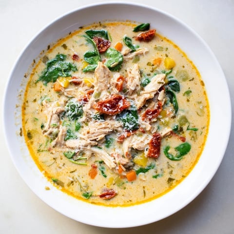 Creamy Tuscan Chicken Soup steaming in a rustic bowl, garnished with extra Parmesan and a drizzle of olive oil.  