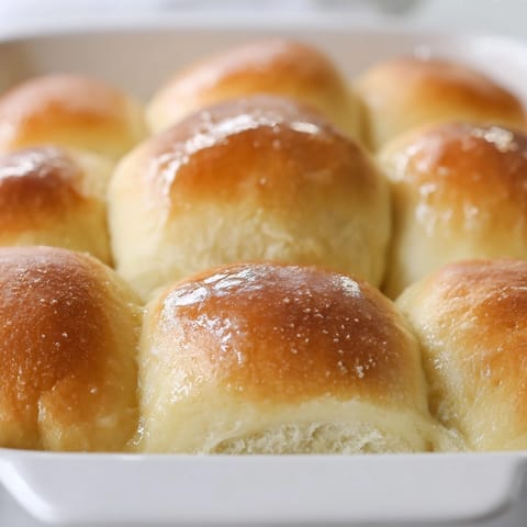 Close-up of soft, warm Fluffy Buttermilk Dinner Rolls in a baking pan, ready to serve.