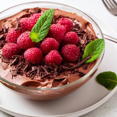 Creamy, dark avocado chocolate mousse with a swirl of fresh raspberries providing a beautiful contrast.