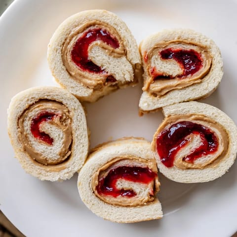 Easy peanut butter and jelly pinwheel rolls, sliced for grabbing, perfect for kid's lunch.