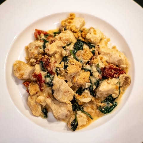 A close-up of a baking dish reveals a rich, savory Marry Me Chicken Casserole, full of flavor.