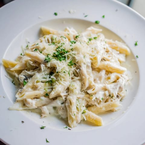 Warm, inviting picture of Tini's Creamy Chicken Pasta, garnished with fresh parsley and Parmesan cheese.