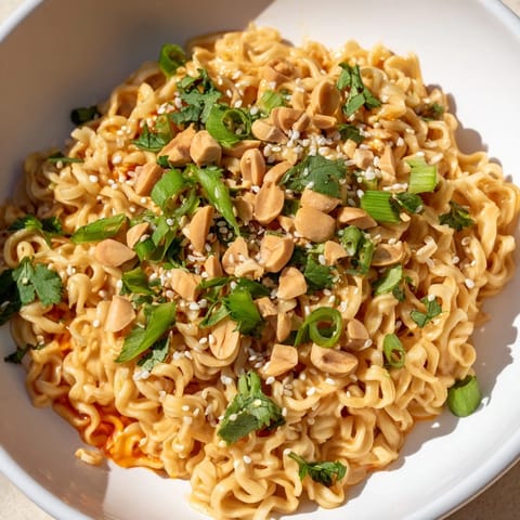 Bowls of vibrant Instant Peanut Thai Sauce Noodles garnished with fresh cilantro and crunchy chopped peanuts.