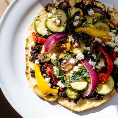 Naan bread pizza with vibrant roasted vegetables and creamy feta, ready to enjoy.