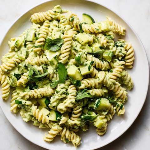 Bright green Green Goddess Pasta Salad featuring al dente fusilli, diced cucumber, and fresh herbs tossed in creamy avocado dressing.