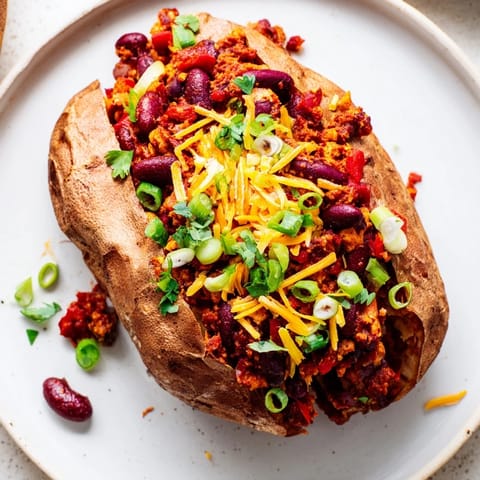 Steaming Chili-Style Baked Potatoes, loaded with savory chili and optional cheddar cheese, ready to eat.