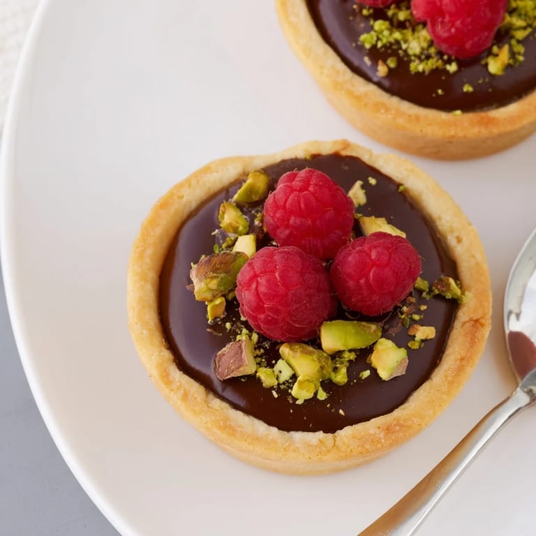 Rich chocolate ganache tartlets, elegantly garnished with fresh berries and gold leaf.