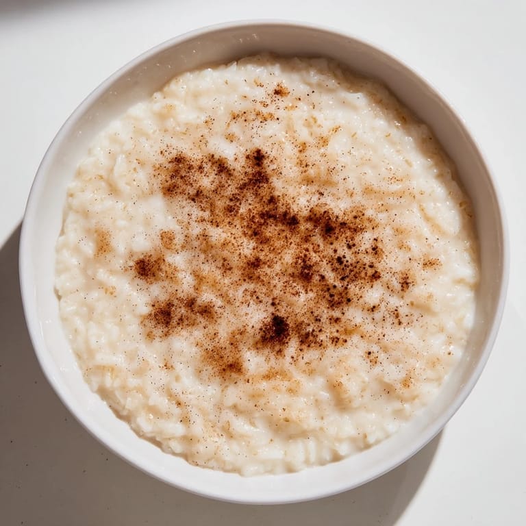 A comforting bowl of rice pudding made from leftover rice, rich with cinnamon and vanilla flavors, ready to eat.