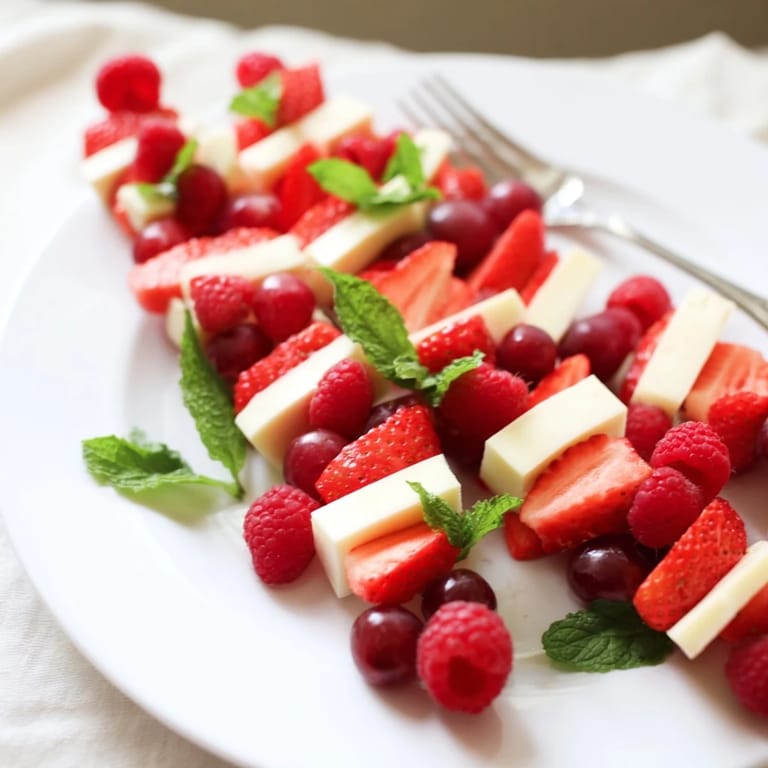 This colorful candy cane stripe fruit and cheese appetizer features layers of red fruits and white cheeses, ready to serve.