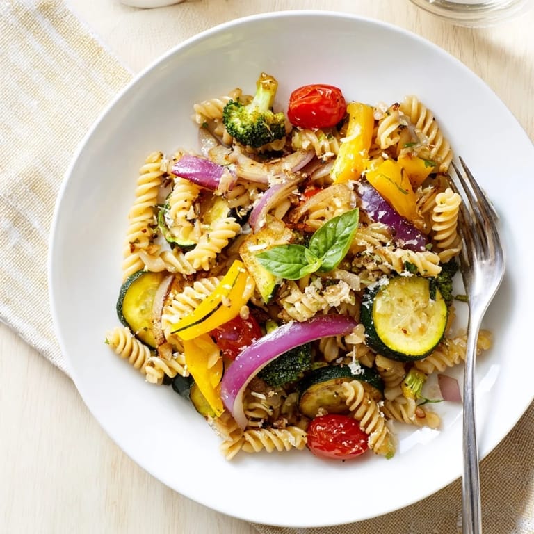 Pasta primavera served in a skillet with fresh basil and melted Parmesan, ideal for a family-style Italian dinner.  