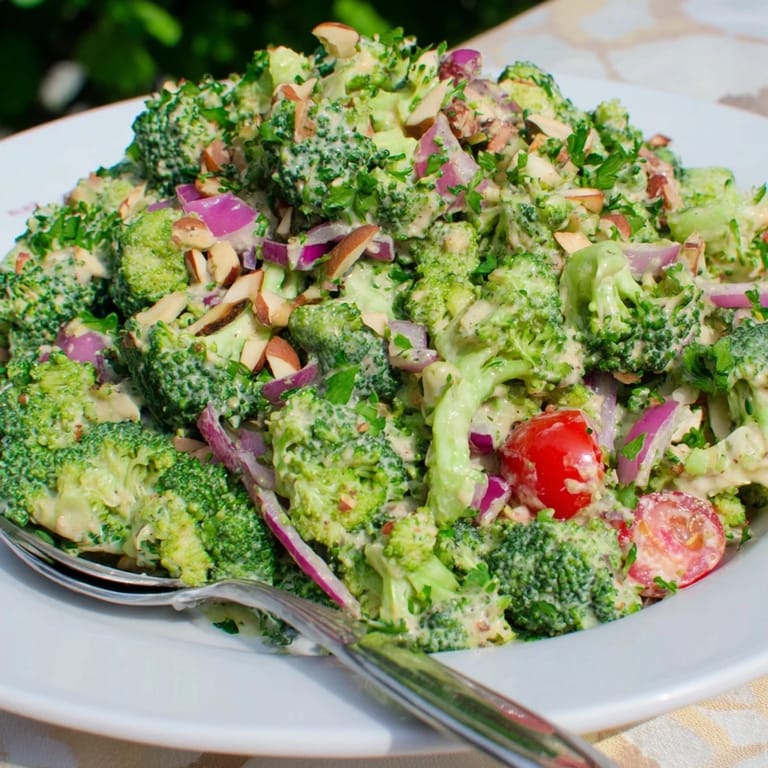 Chilled Garlic Parmesan Broccoli Salad with crunchy almonds, fresh parsley garnish, and a creamy, garlicky dressing drizzled over florets.