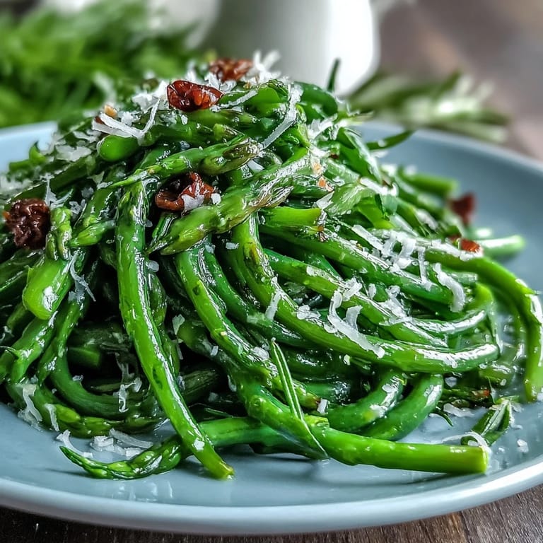 Crisp asparagus ribbons and sweet peas tossed in a zesty lemon dressing, topped with Parmesan and pine nuts for a bright, fresh salad.