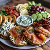 A vibrant spring brunch board with smoked salmon, assorted bagels, and creamy whipped cream cheese, garnished with fresh herbs and lemon.