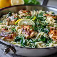 Creamy lemon orzo with chicken and spinach, featuring tender chicken, bright lemon zest, and fresh spinach in a cozy skillet meal.